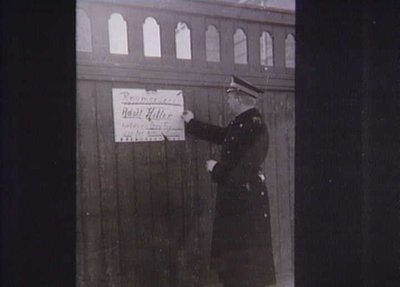 Betjent fjerner en illegal plakat i april 1944