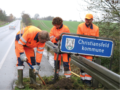 Medarbejdere ved Christiansfeld Kommune graver det gamle kommuneskilt op.